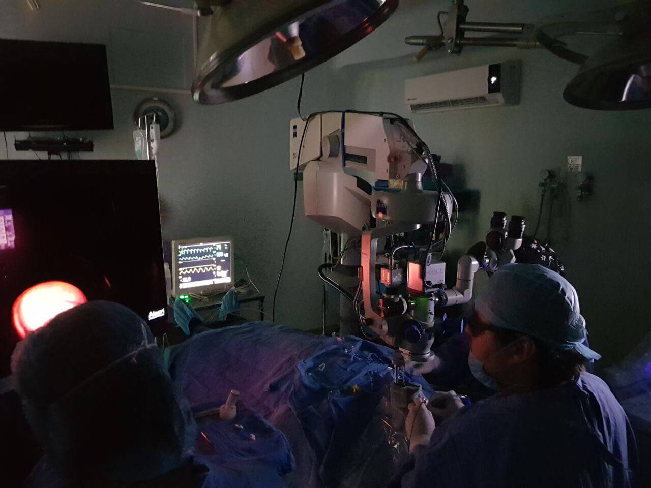 Foto de cirugía donde aparece el Dr. Alain Matabuena Dorado con láser en un cuarto oscuro.